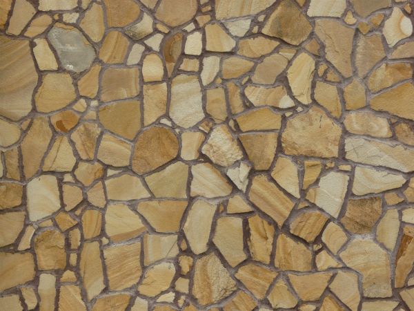 Peach-colored rough flat stone set in dark grey concrete.